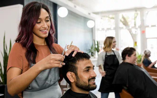 Un coiffeur coupe les cheveux d'un client dans un salon de coiffure.