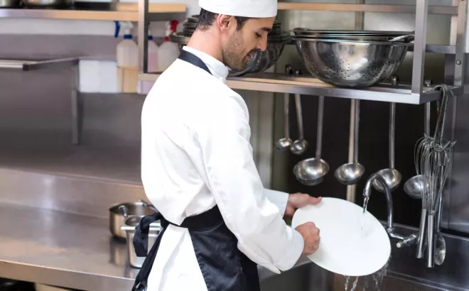 Een jonge man die zijn flexi job als afwasser uitvoert