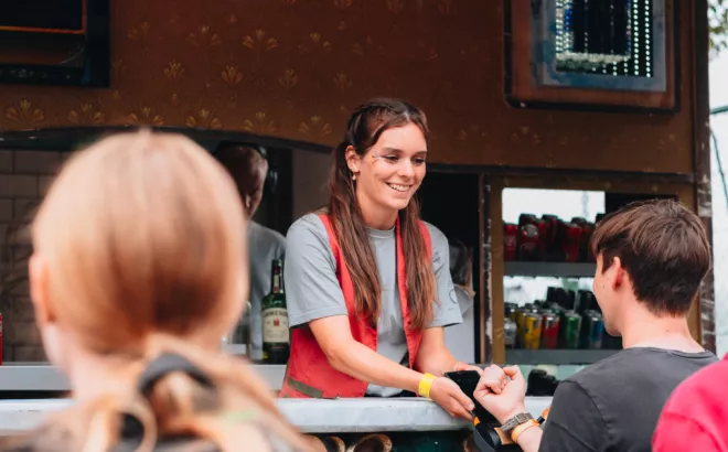 Une femme de bonne humeur effectuant son job d'étudiante derrière le bar de Tomorrowland.