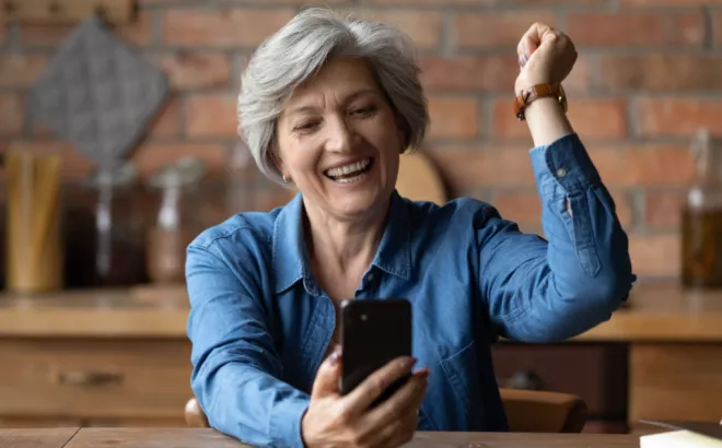 Une dame retraitée qui a trouvé avec enthousiasme un flexi-job grâce à un smartphone